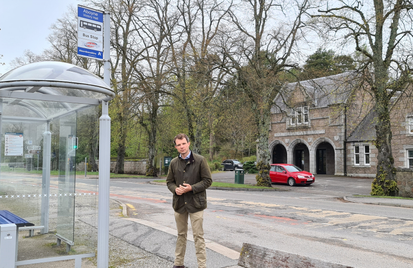 Andrew Bowie MP beside a bus stop in Aboyne.