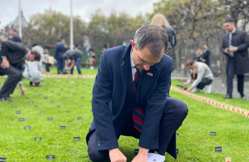 Andrew planting a cross and poppy in the Parliament remembrance garden.