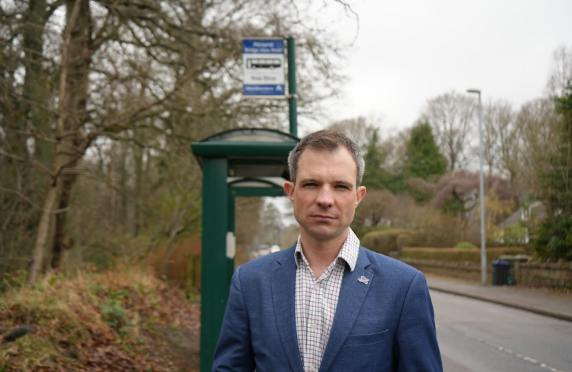 Andrew Bowie standing by a bus stop.