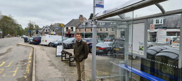 Andrew beside a bus stop.