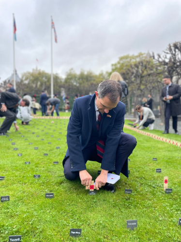 Andrew planting a cross and poppy in the Parliament remembrance garden.